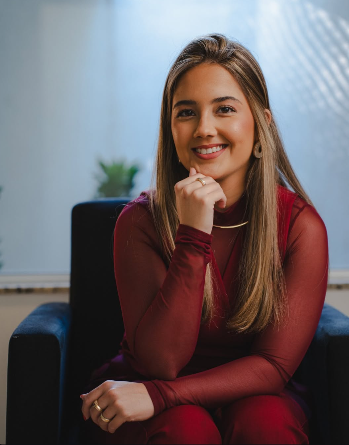 Amanda Lino sentada em uma poltrona, sorrindo